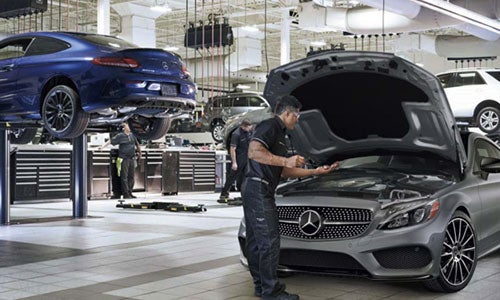 Technician performing engine service on Mercedes-Benz vehicle
